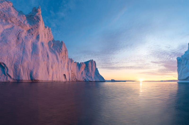 Early morning summer alpenglow lighting up icebergs during midnight season.